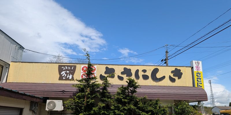青空の下、黄色い「ささにしき」の看板を掲げたお店の外観