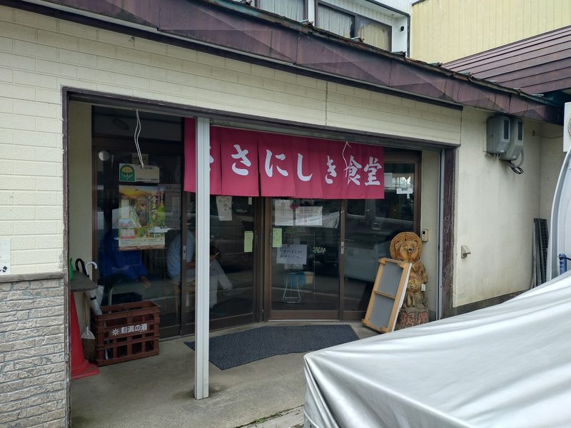 赤い「ささにしき食堂」ののれんがかかった入口