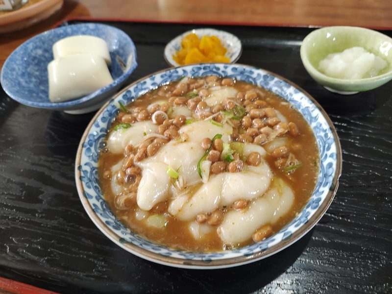 藍色の模様の器に盛った納豆餅と、漬物、大根おろし