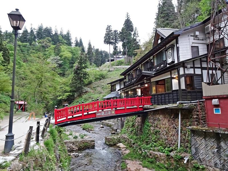 銀山川にかかる赤い橋と、川沿いに並ぶ木造の旅館